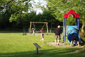 Ein Spielplatz mit Schaukeln, einer Rutsche und einem Picknicktisch.