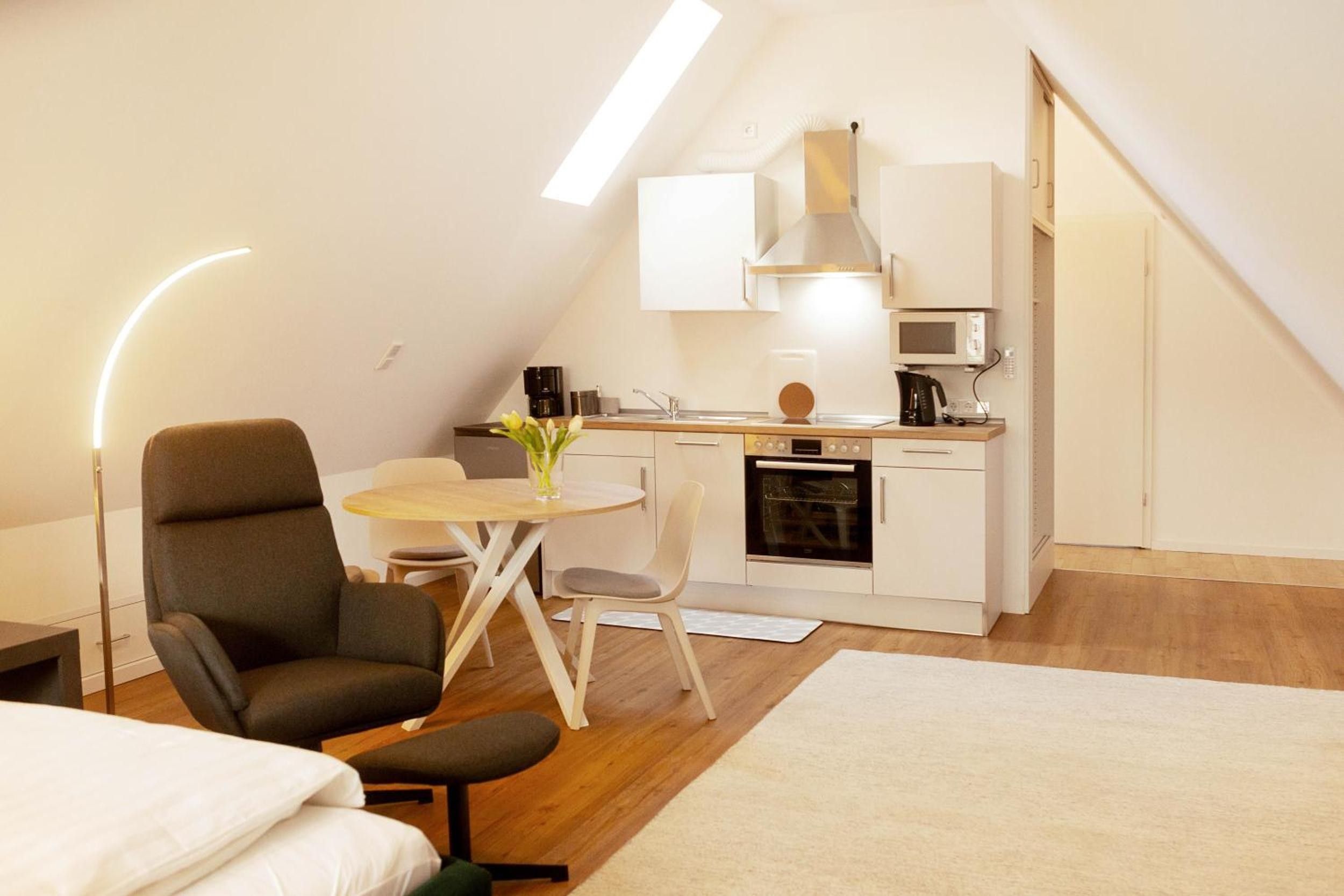 En kompakt, moderne lejlighed med tekøkken, spiseplads og soveområde.