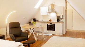 Ein kompaktes, modernes Apartment mit Küchenzeile, Essbereich und Schlafgelegenheit.