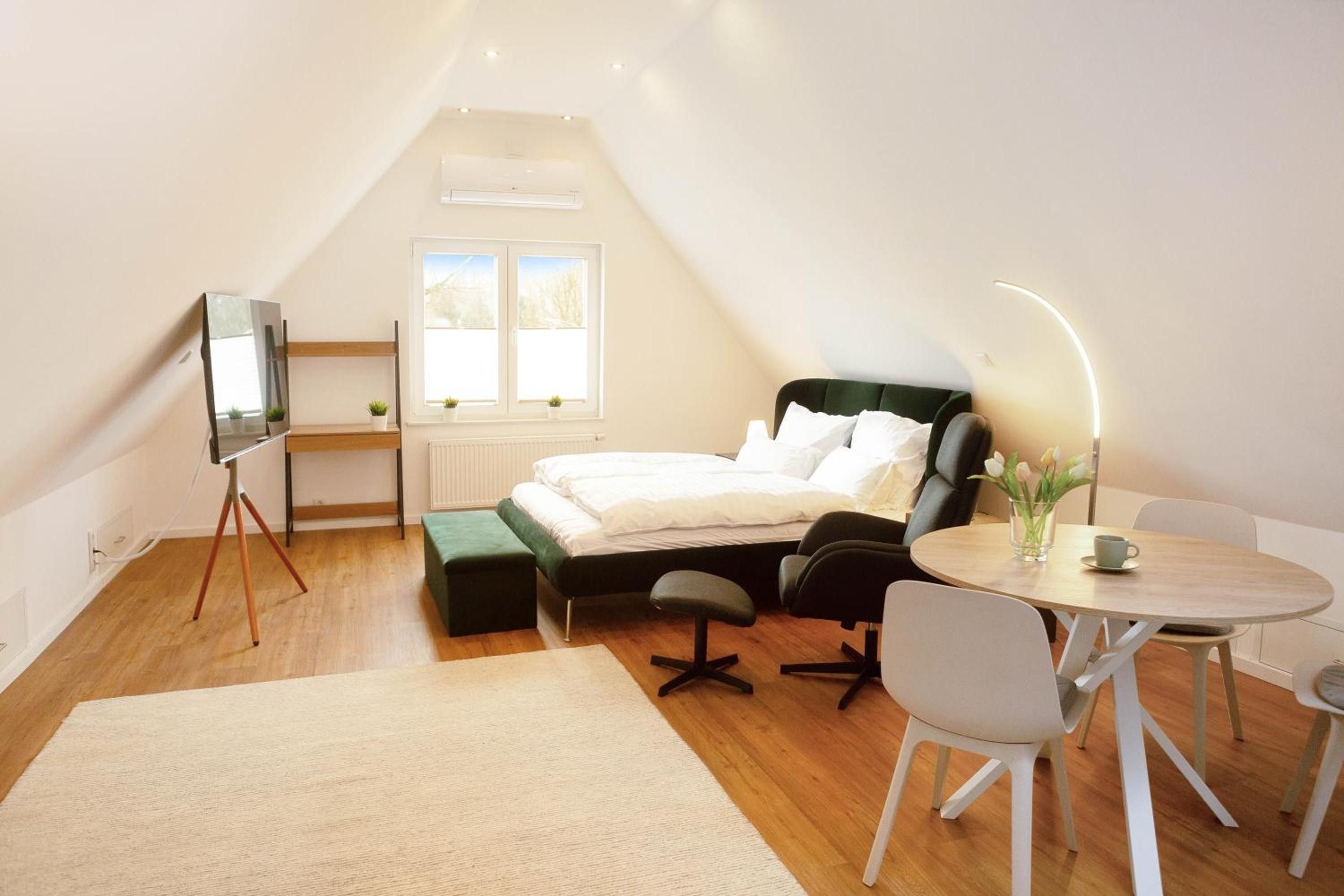 Et moderne soveværelse med loft-stil loft, en seng, et skrivebord og et spiseområde.