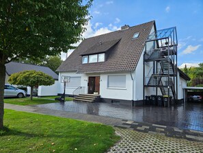 A two-story residential building with a sloped roof, a visible staircase, and a garage. - Room 'Haus Salinen Loft 5' with Balcony, Wi-Fi and Air Conditioning (Bad Rothenfelde)