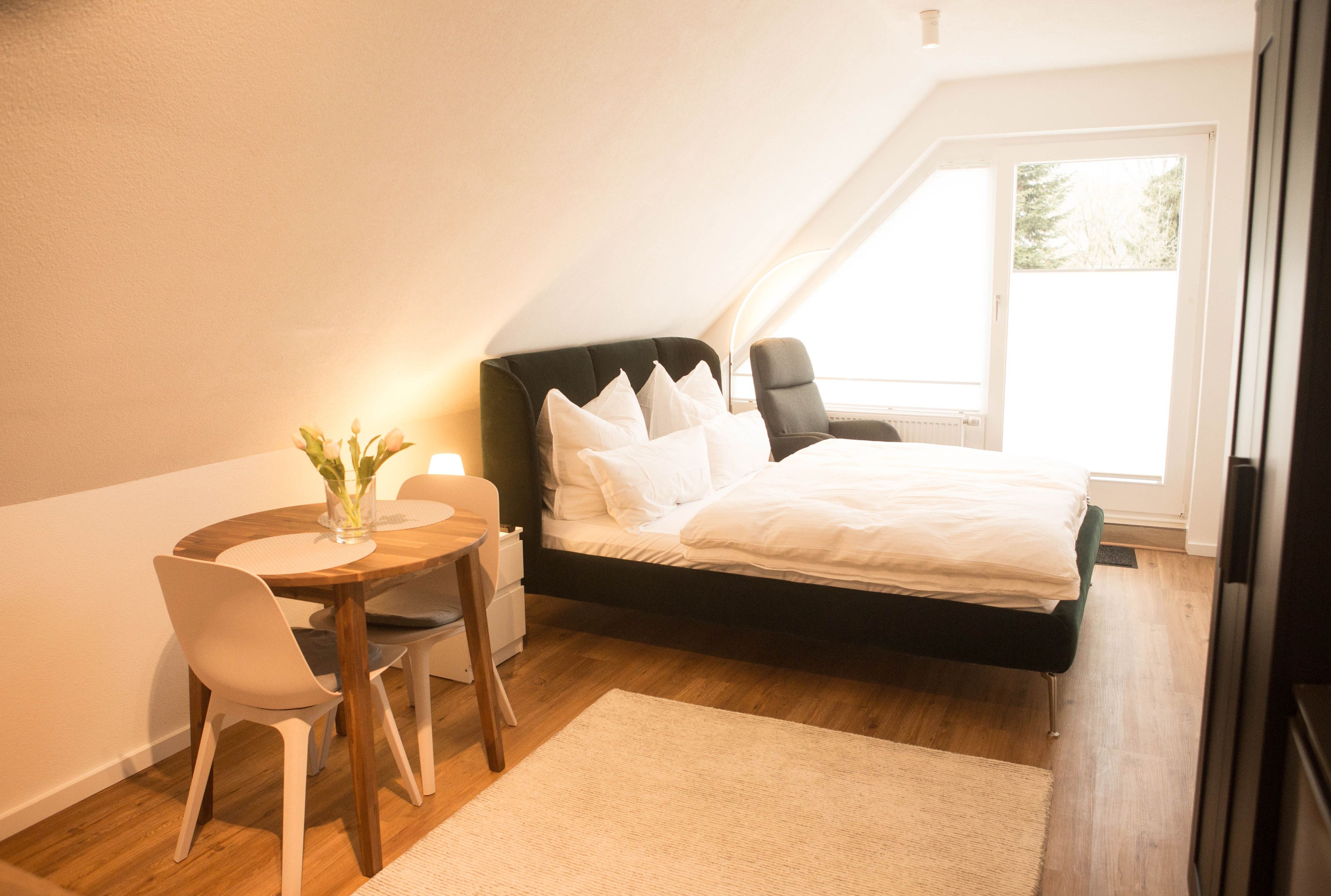 Une chambre à coucher avec un lit, une table de chevet, une chaise et une fenêtre.