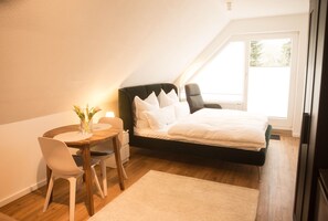 Una camera da letto con un letto, un comodino, una sedia e una finestra.