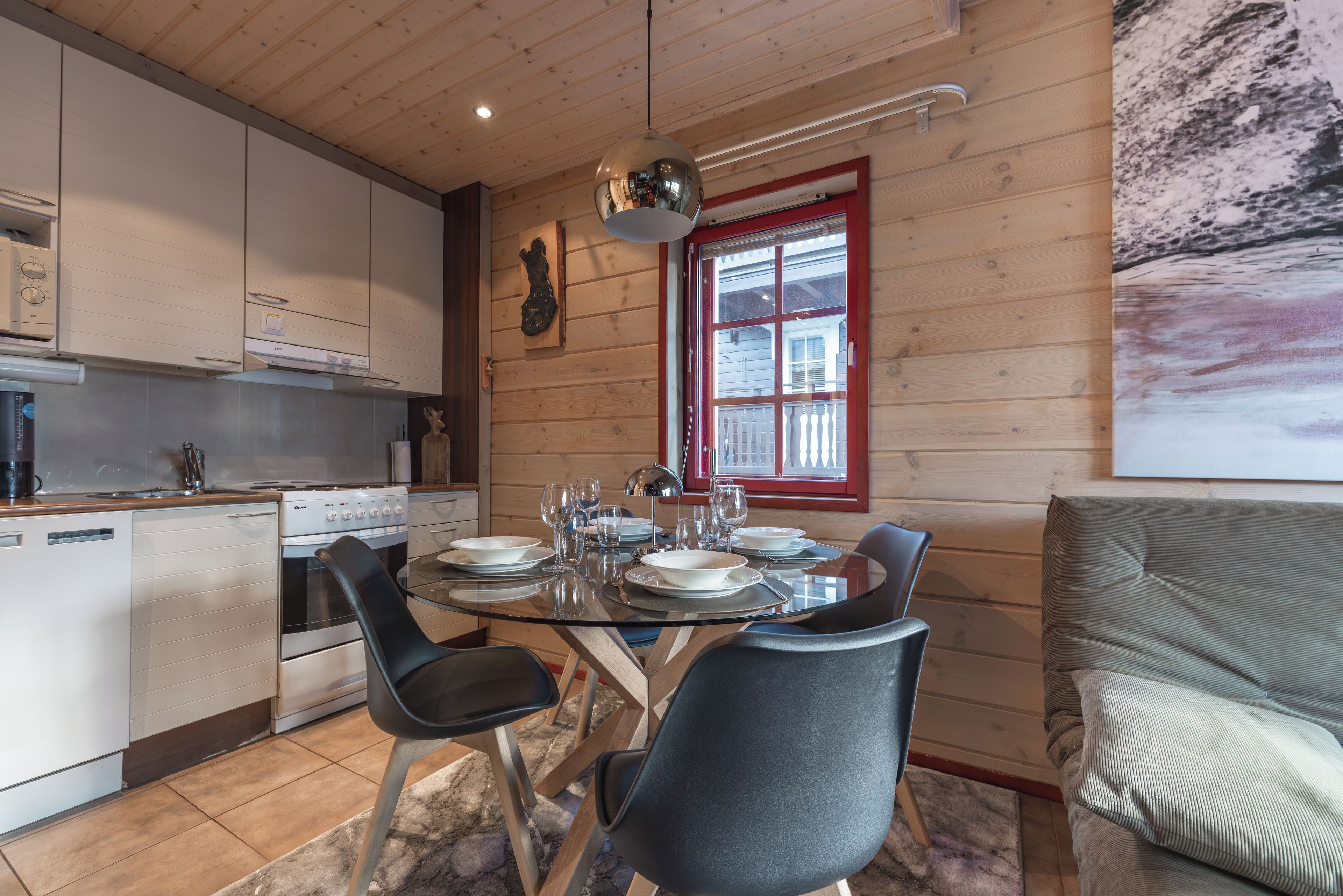 Une cuisine moderne avec un coin repas, comprenant une cuisinière, un four et une table à manger pour quatre personnes.