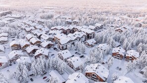 A snow-covered residential area with multiple houses and a central building with balconies. - Levin Otava - Comfy Apt in Levi Centre (Kittilä)