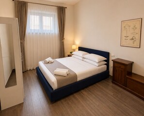 Une chambre d’hôtel avec un lit, une table de chevet, une lampe, une armoire et un tableau encadré au mur.
