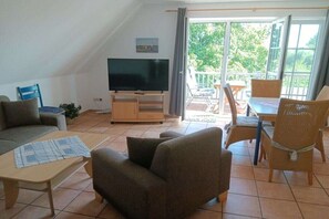 Un salon comprenant un téléviseur, un canapé et un coin repas avec des chaises.