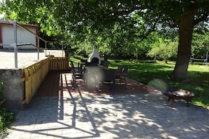 Eine Außenpatio mit Backsteinboden, Holzfence und Grillplatz.