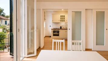 A modern kitchen with white cabinets, a dining table with chairs, and a sliding glass door leading to an outdoor area.