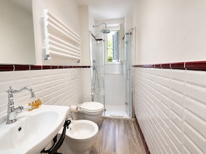 Een badkamer met een wastafel, toilet, bidet en douche.