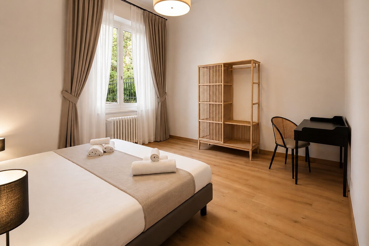 Een hotelkamer met een bed, een bureau, een stoel, een kledingkast en een raam met gordijnen.