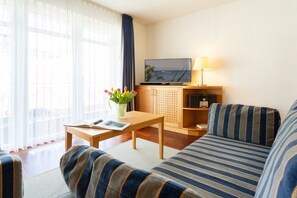 Ein modernes Wohnzimmer mit einer Couch, einem Couchtisch, einem Fernseher und einer Lampe.