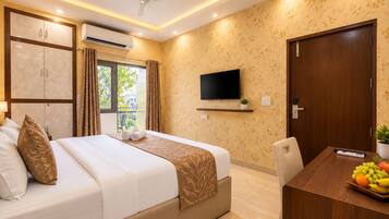 A hotel room with a bed, a TV, a desk with fruit, and a balcony.