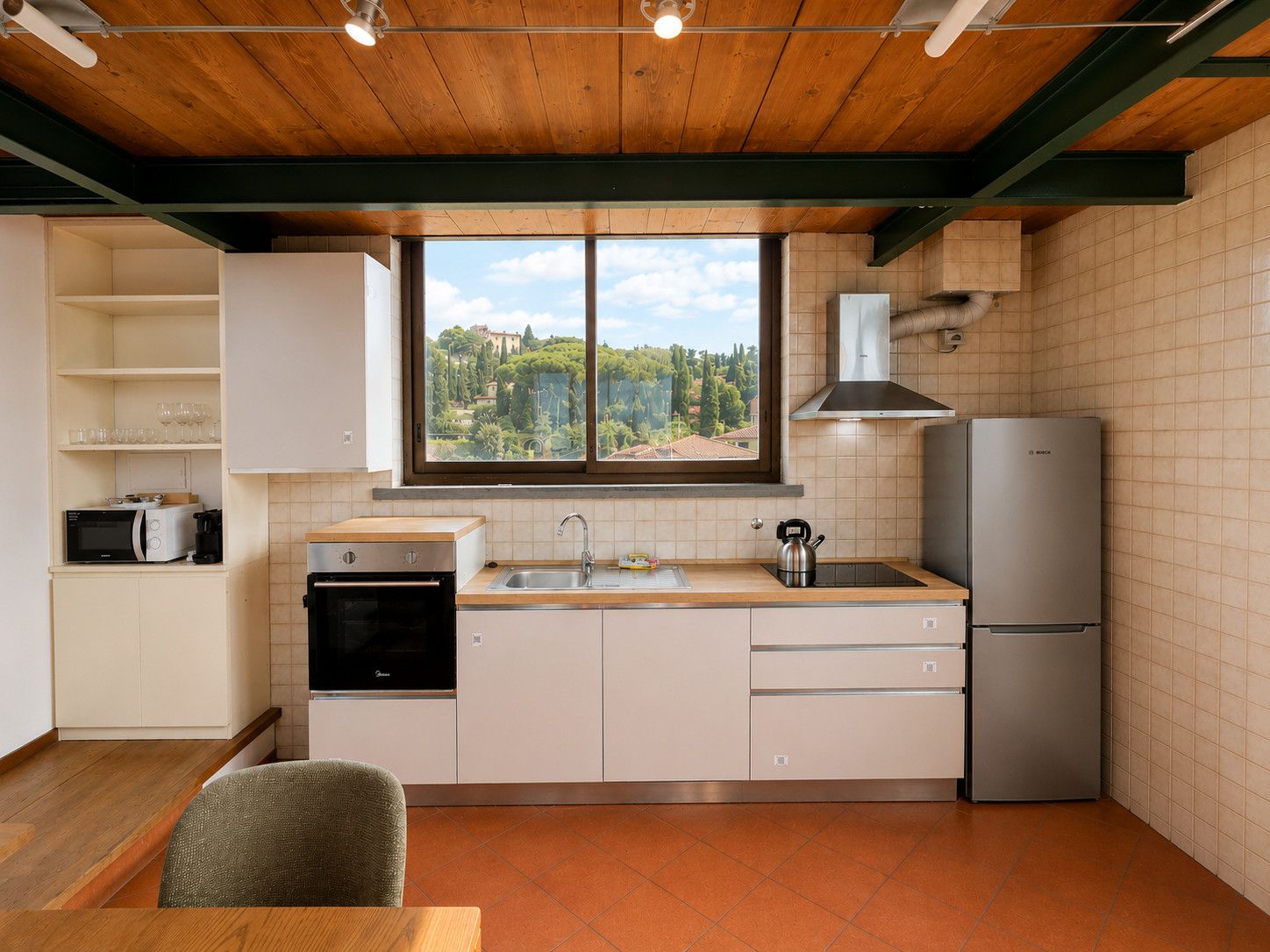 A modern kitchen with a view of a mountainous landscape, a built-in oven, a sink, and a refrigerator.