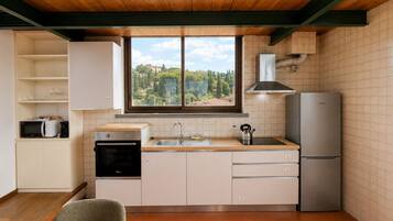A modern kitchen with a view of a mountainous landscape, a built-in oven, a sink, and a refrigerator.