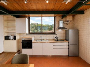 Una cuina moderna amb vista a un paisatge de muntanya, forn de sobre, rentaplat i nevera.