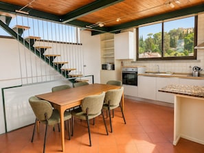 Una cuina moderna amb zona de menjador, una escala i vista a l'exterior.