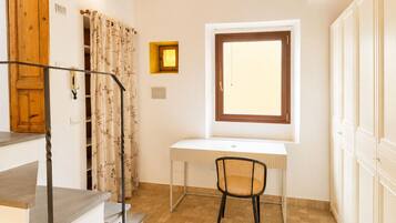 A small, well-lit room with a desk, chair, and a window.