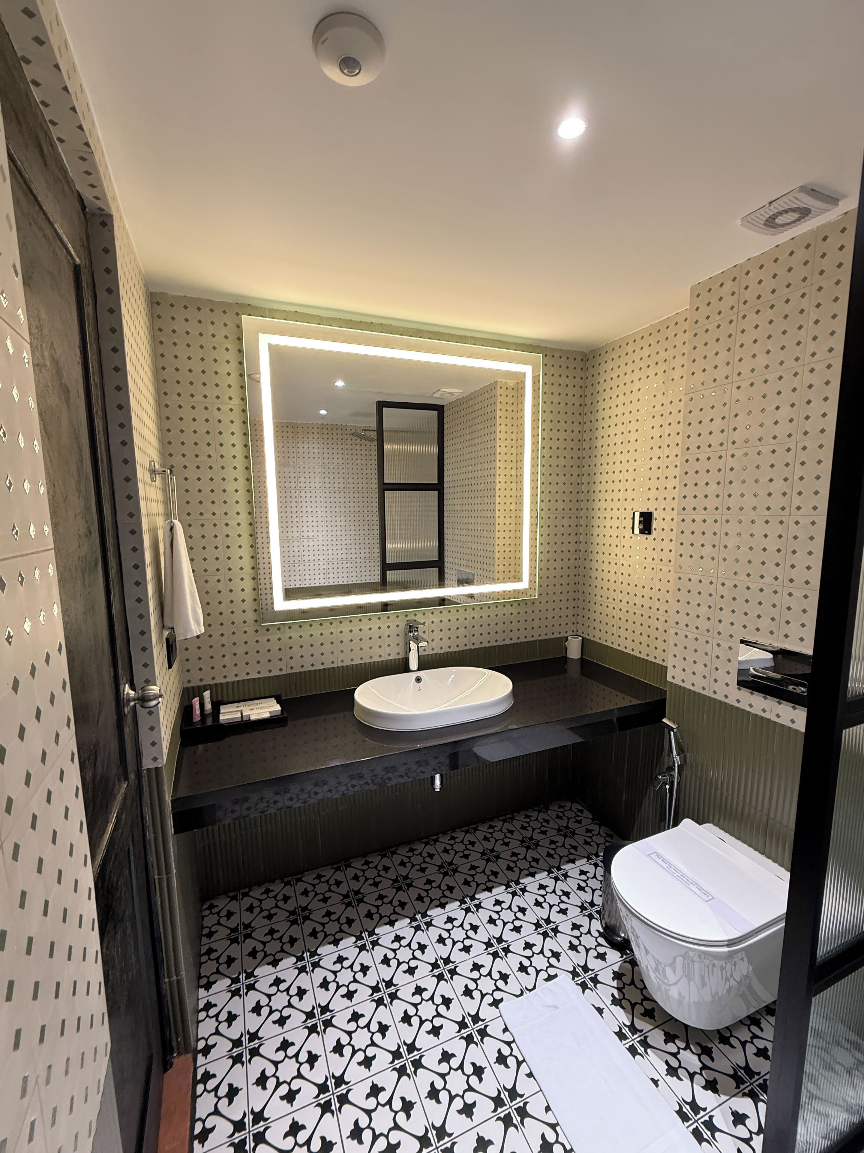 Un baño moderno con un espejo grande, un lavabo y un inodoro.