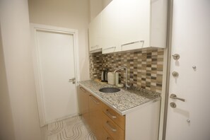A small kitchen with a sink, cabinets, and a patterned floor.
