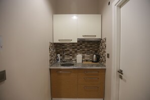 Una cocina funcional con armarios blancos, encimera de granito y salpicadero a cuadros.