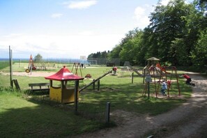A playground with various play equipment including swings, slides, and climbing structures. - Beach house type "sailor" (Schashagen OT Bliesdorf-Strand)
