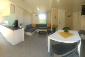 A compact living space with a kitchenette, a dining area, and a seating area with a sofa and a table. - Beach house type "sailor" (Schashagen OT Bliesdorf-Strand)