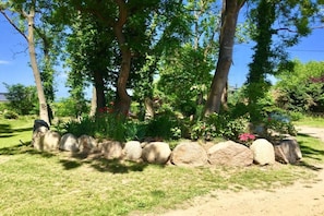 A garden with a variety of trees and a stone border. - Holiday apartment with 1 bedroom (Bastorf (OT Kägsdorf))