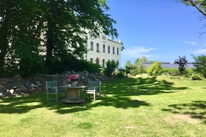 A well-maintained lawn with a stone wall and a large building in the background. - Holiday apartment with 1 bedroom (Bastorf (OT Kägsdorf))