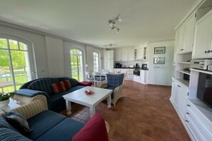 A spacious living area with a sofa set, a dining table, and a kitchen in the background. - Strandpalais Kühlungsborn "Starboard" (Kühlungsborn)