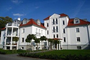 A multi-story building with a red roof, white walls, and a balcony on the second floor. - Strandpalais Kühlungsborn "Starboard" (Kühlungsborn)