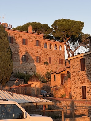 Un edifici de pedra amb diverses finestres i un cotxe estacionat al davant.