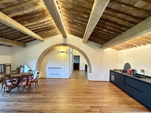 Un interior amb zona de menjador, cuina i sostre arquejat.
