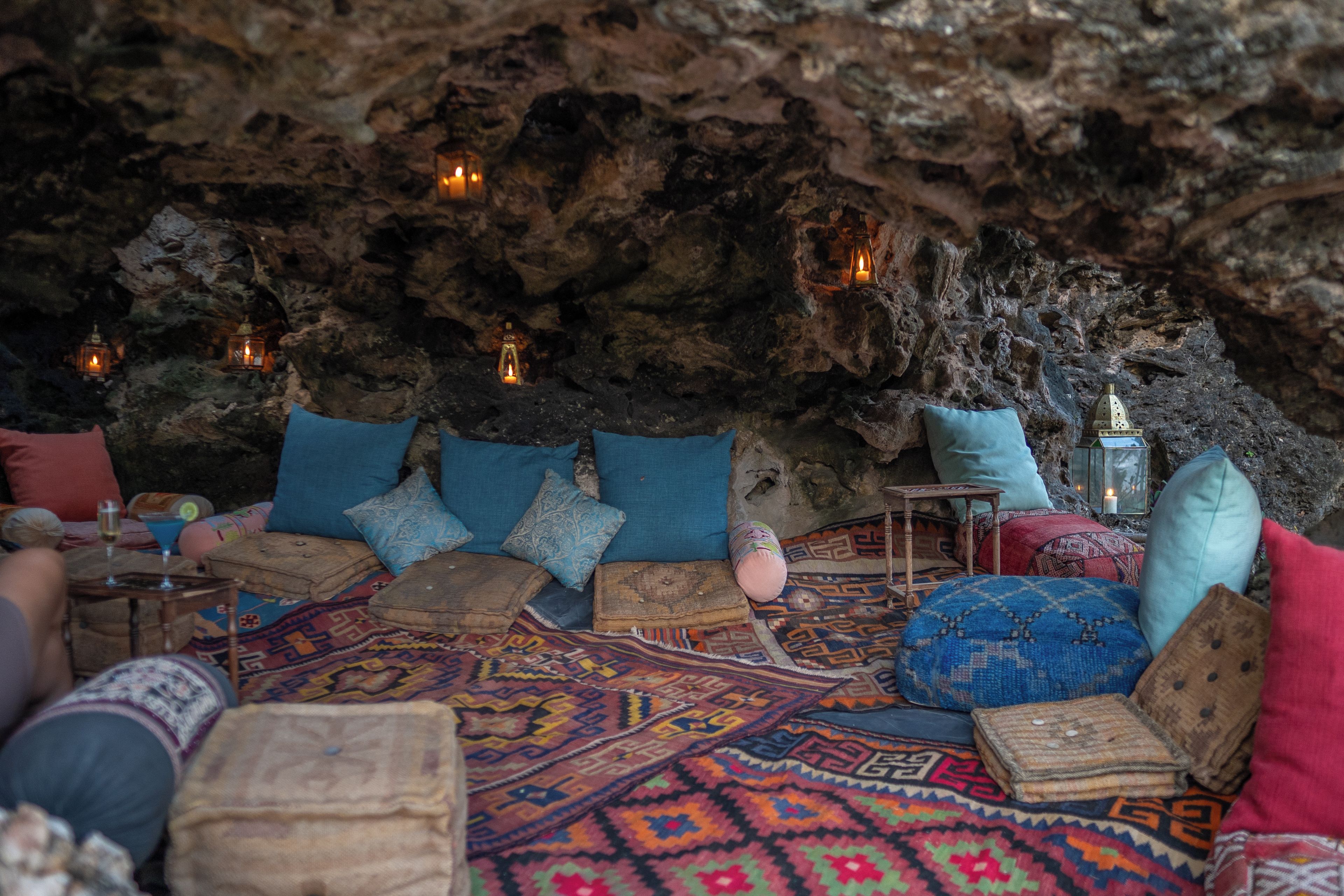 Un interior acogedor que recuerda a una cueva, con asientos, cojines y velas.
