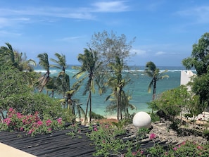 Vista costera con palmeras, una playa y una estructura esférica grande.