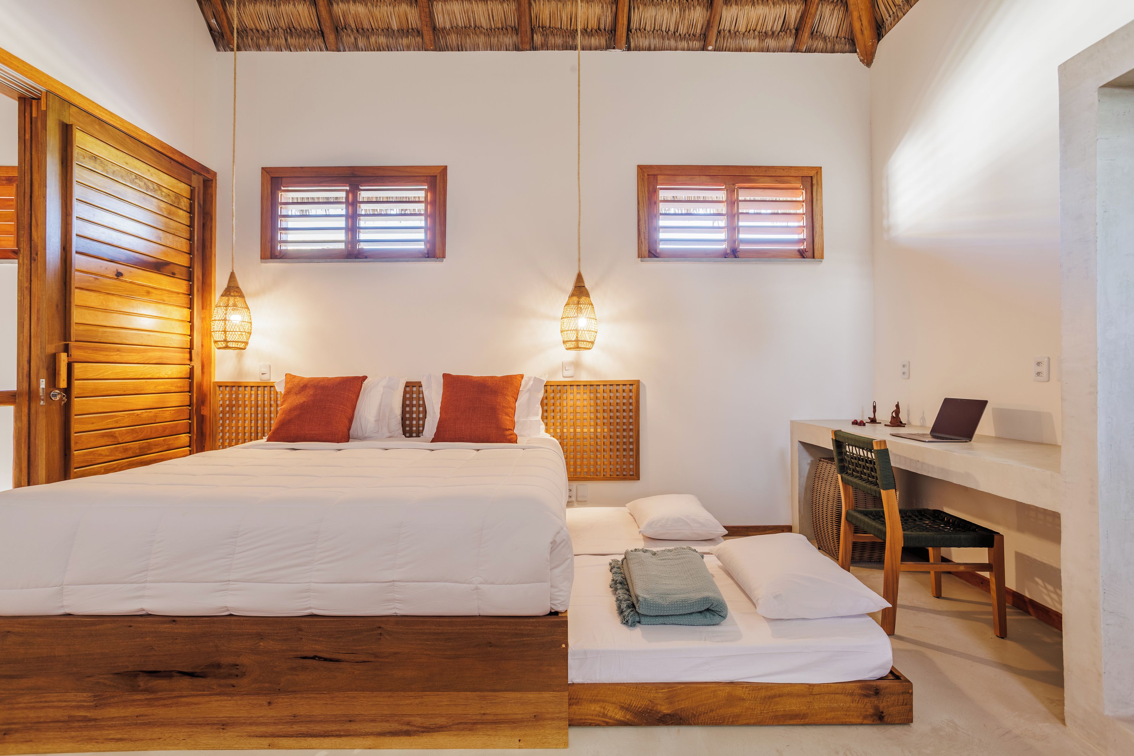 A bedroom with a wooden bed, two bedside tables, a desk, and a chair.