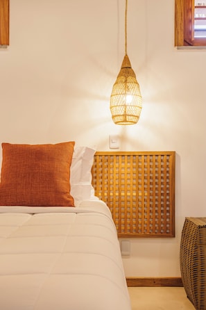 A bed with a white and orange pillow, a wooden headboard, and a hanging light fixture. - Casa Ariah Luxury Villas (Cruz)