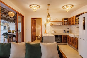 Una cocina moderna con armarios de madera, un refrigerador blanco y una zona de comedor con mesa y sillas.