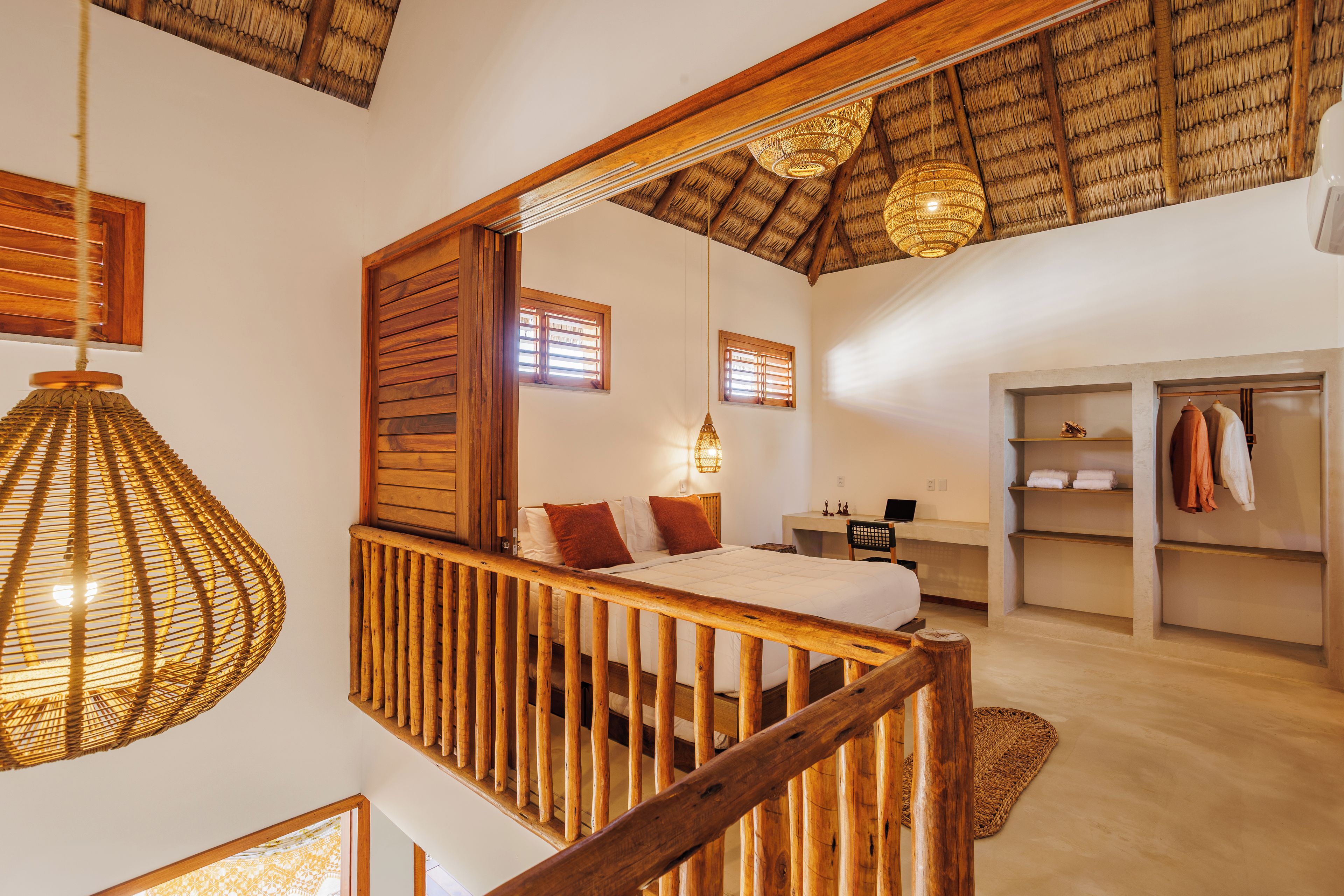 Quarto com cama de madeira, escrivaninha e guarda-roupa.