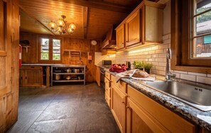 A wooden interior with a kitchen area featuring cabinets, a countertop, and a sink. - Chalet Béziere, Central Morzine – 5 Bed, Sleeps 15, Hot Tub, Garden & Fireplace (Morzine)