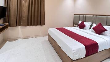 A hotel room with a bed, a TV, and a wall-mounted shelf.