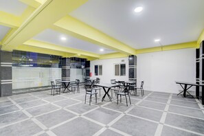 Un salón de conferencias con mesas, sillas, paredes de vidrio y techo amarillo.