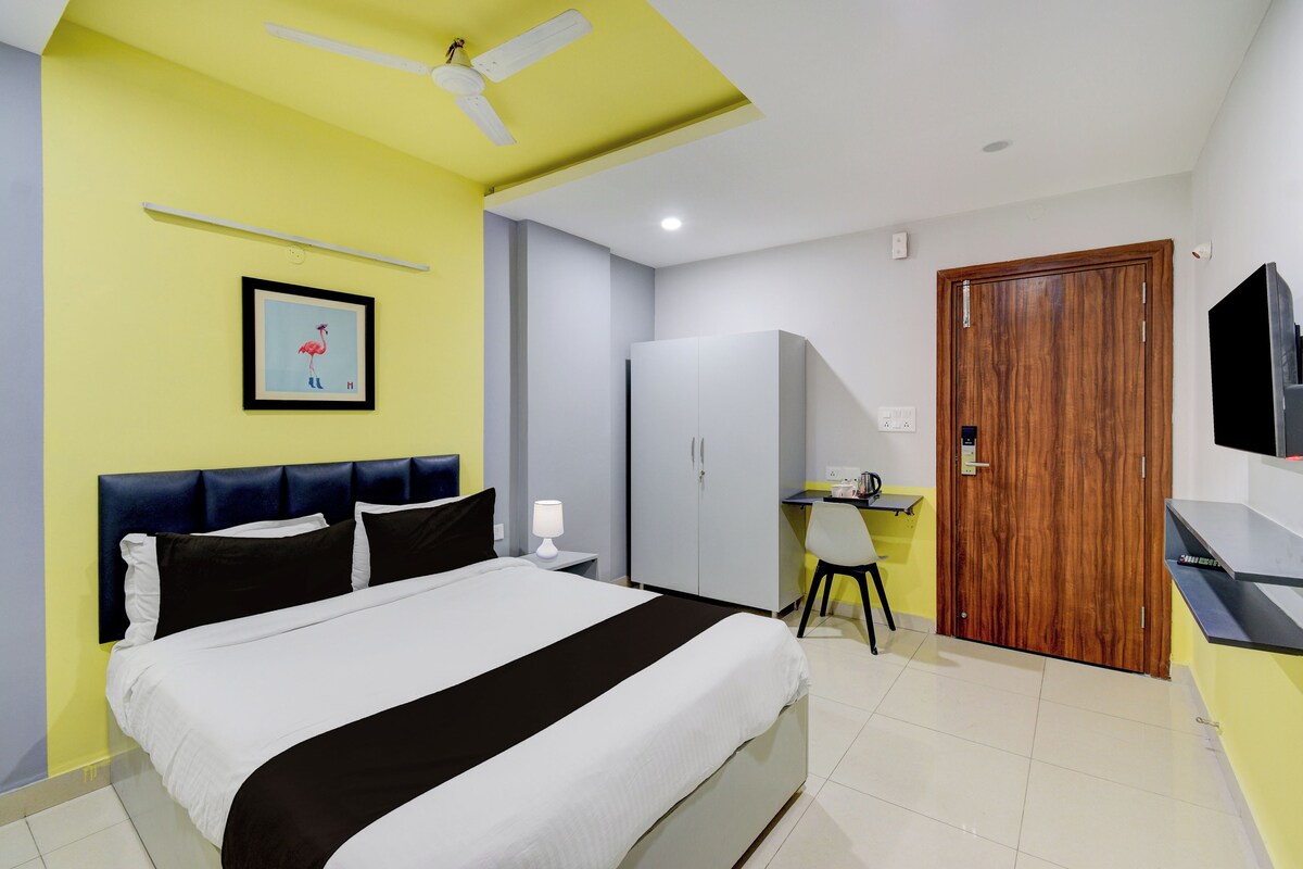 Una habitación de hotel con cama, escritorio, armario, ventilador de techo y televisión.