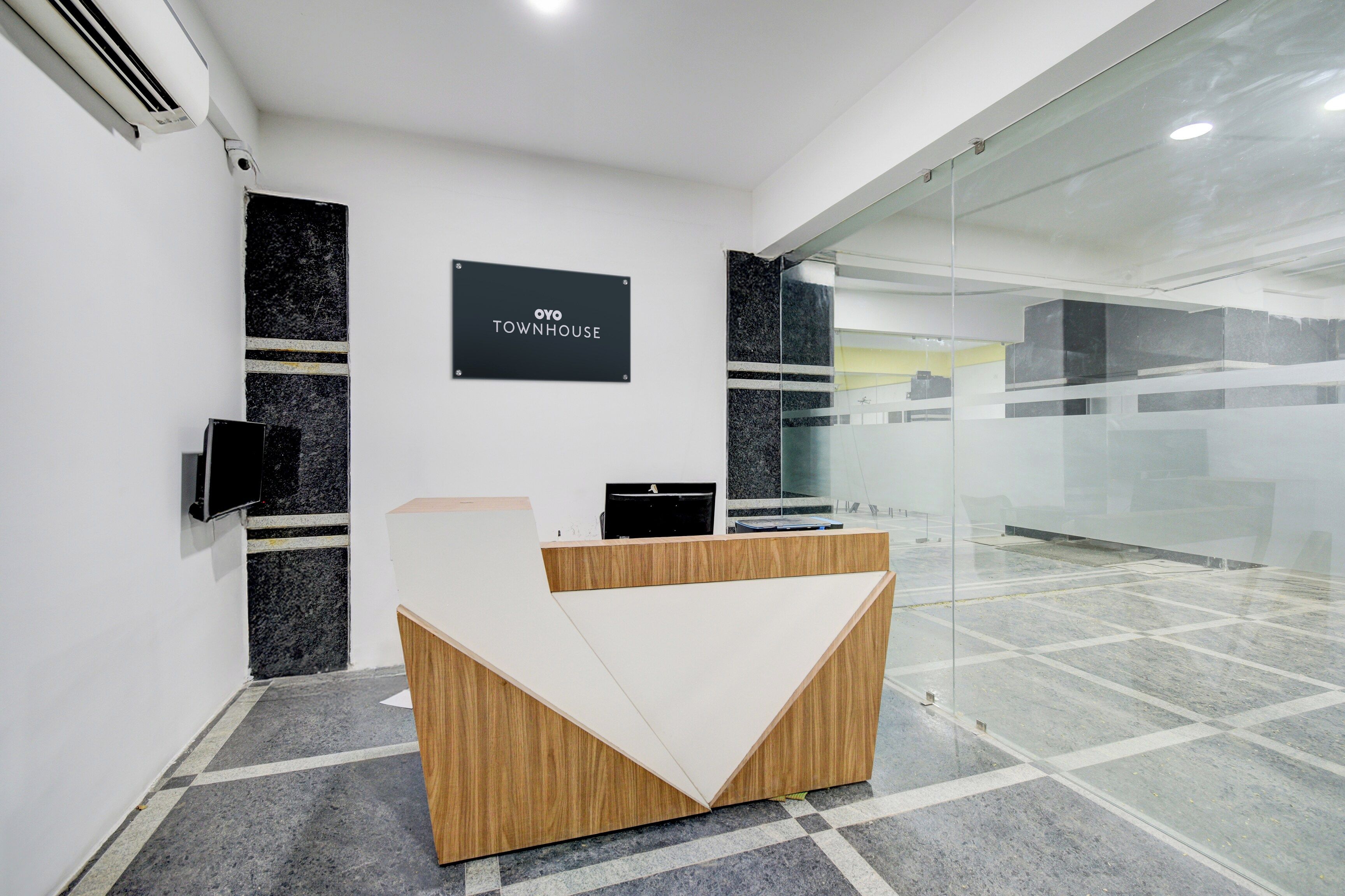 Una recepción con un letrero negro que dice 'OYO TOWNHOUSE'.