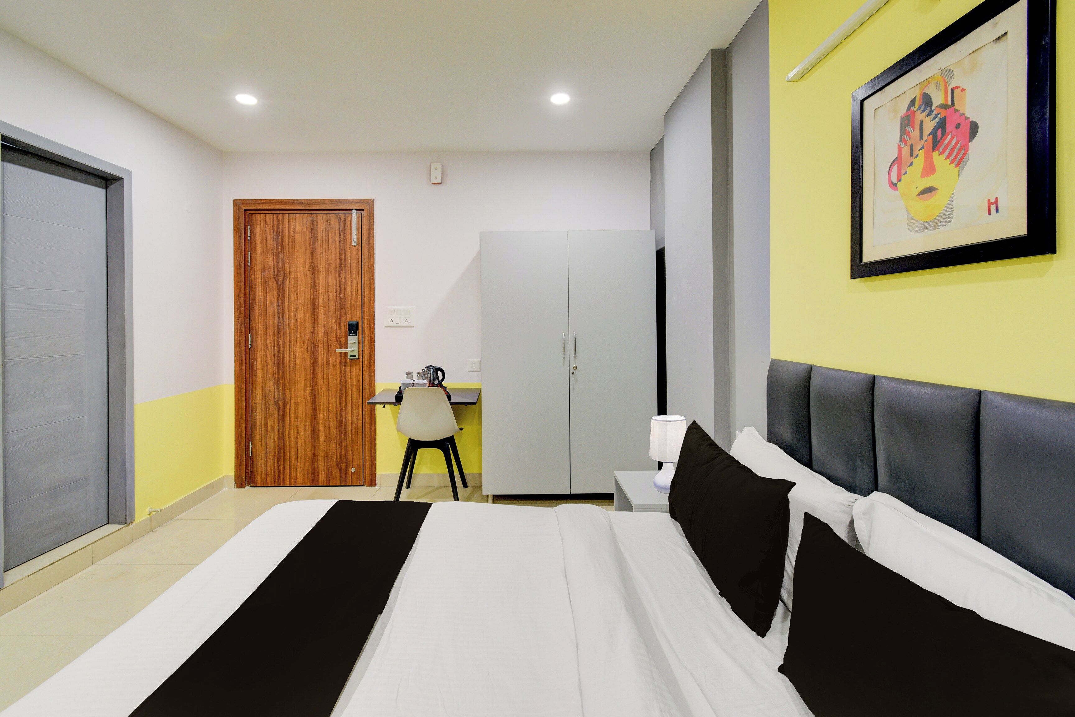 Quarto de hotel com cama, escrivaninha, cadeira e guarda-roupa.