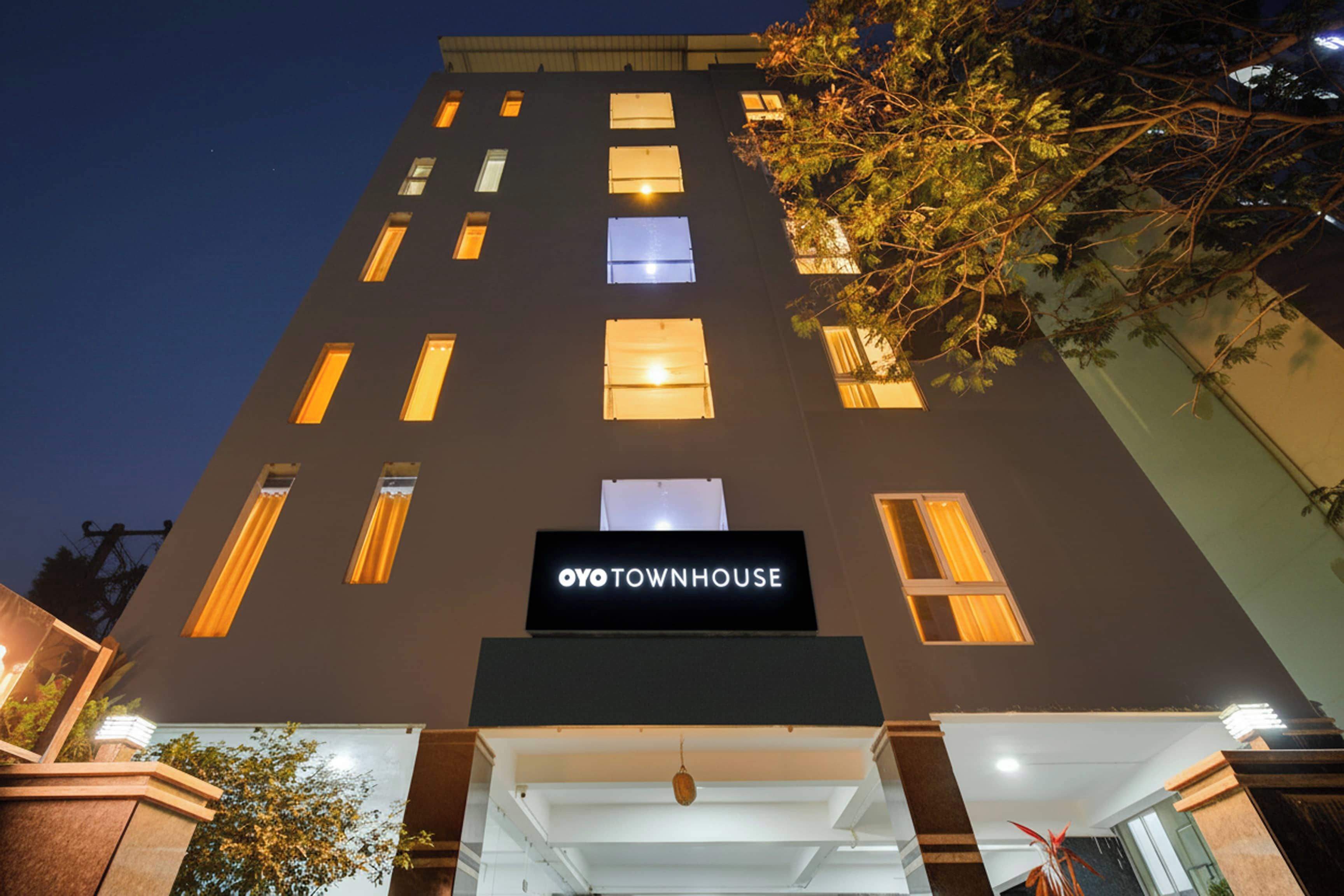 Un edificio de varios pisos con un cartel que dice 'OYO TOWNHOUSE' en la entrada.