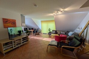 A living room with a television, seating, and a staircase. - "Jonas" in the Riwa House (Kölpinsee)