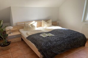 A bedroom with a bed, pillows, a bedside table, a lamp, and a potted plant. - "Jonas" in the Riwa House (Kölpinsee)