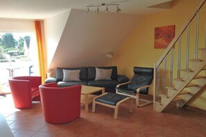 A living room with a sofa, two armchairs, a coffee table, and a staircase. - "Jonas" in the Riwa House (Kölpinsee)