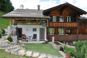 Eine Holzhütte mit Balkon, einer Steinstatue und einer kleinen Sitzecke im Freien.